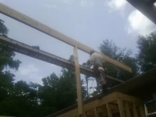 Carpenter setting a ridge beam over a new addition frame — Ice Dam Removal by Roofing Brothers in Sweet