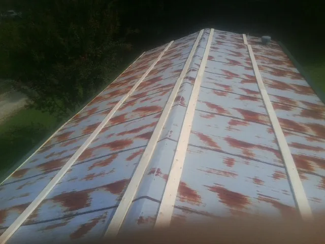 Rusted metal roof panels with new wood purlins before replacement — Storm Damage Roof Repair in Sweet by Roofing Brothers