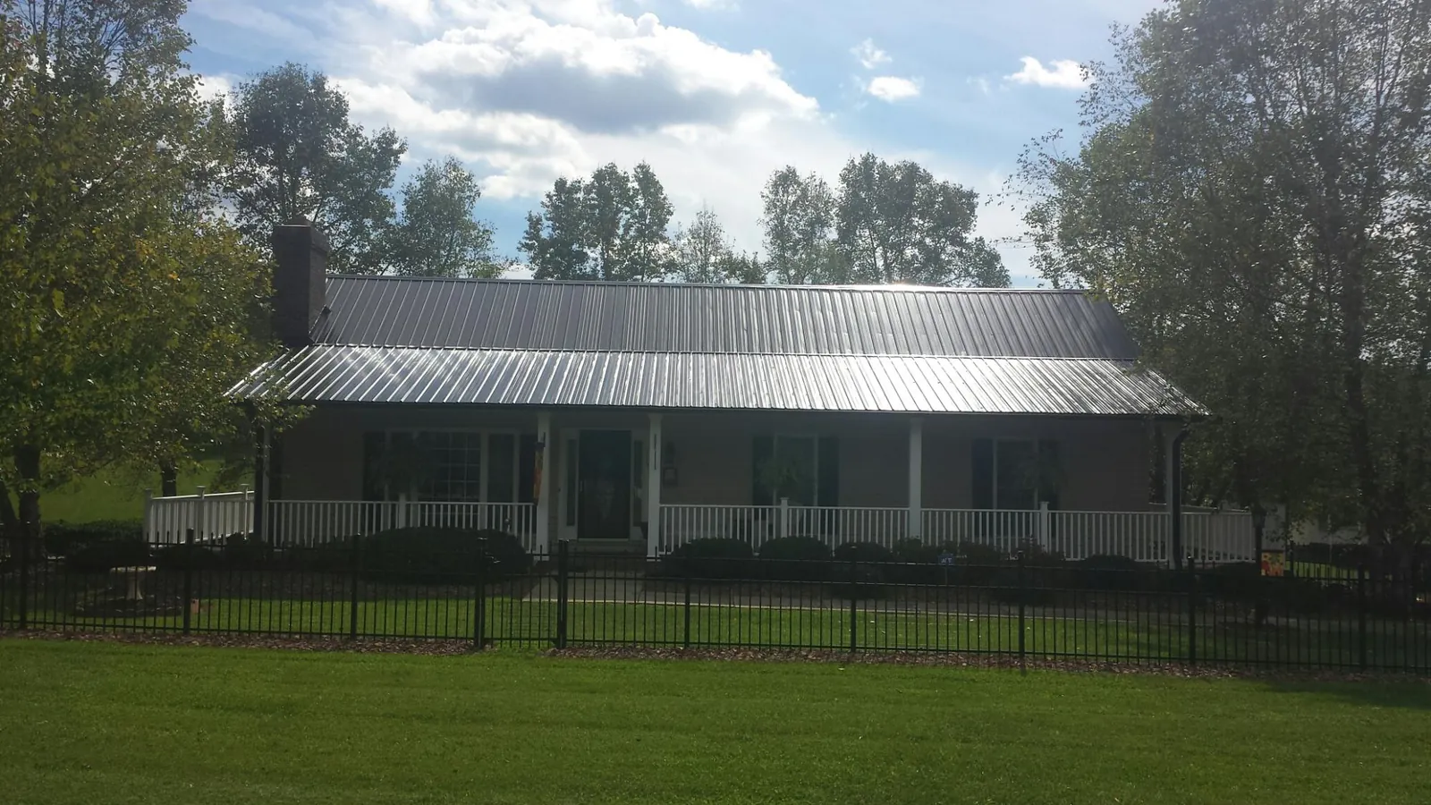 Gray metal roof on a brick ranch with a full width front porch — Gutter Guard Installation work by our crew in Sweet