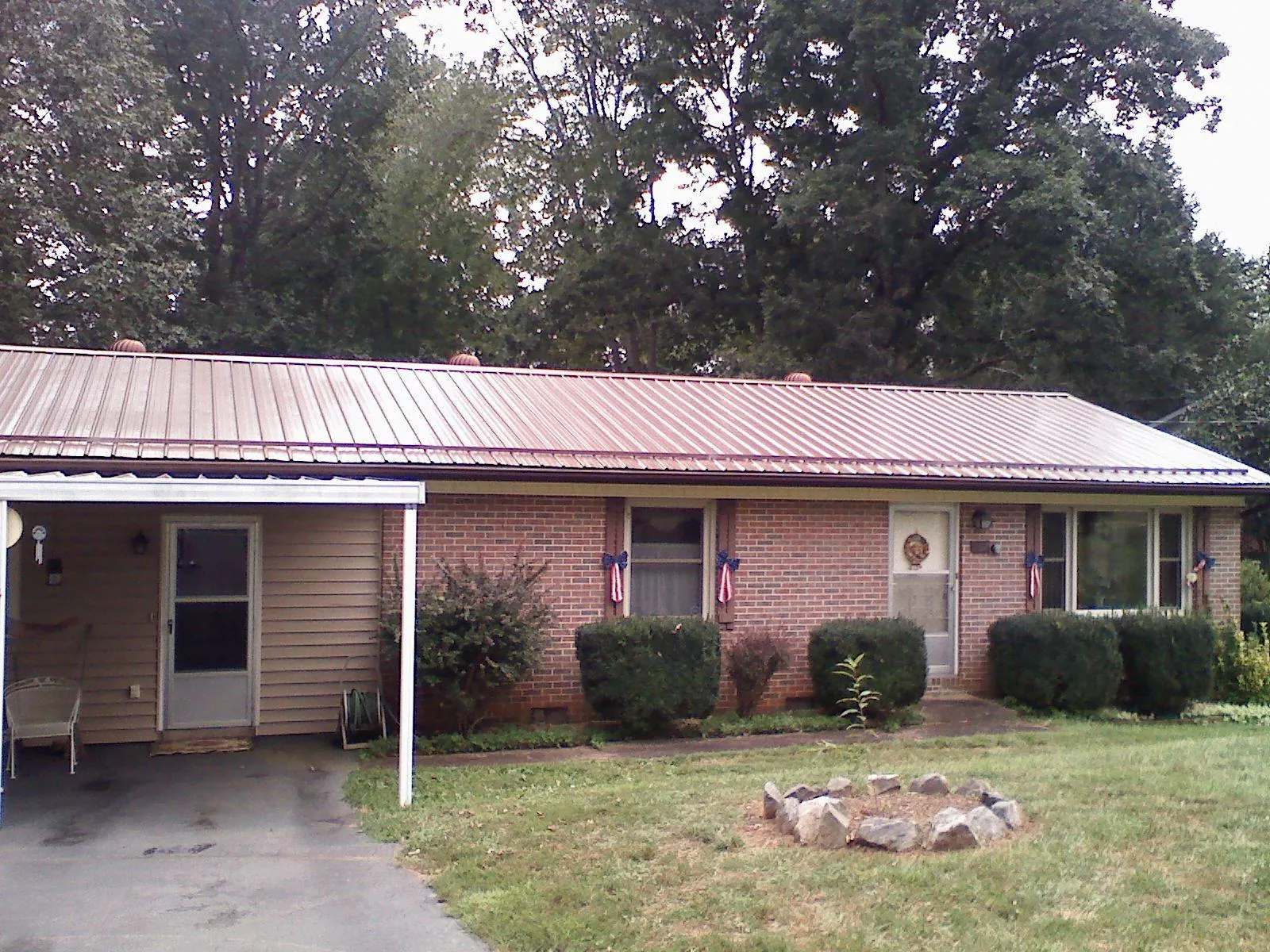 Bronze metal roof and carport on a brick ranch home — Roof Repair work by our crew in Sweet