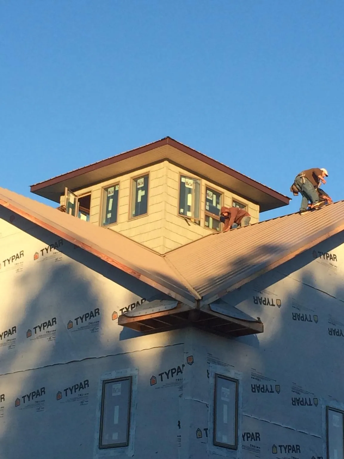 Roofers working around a rooftop cupola on a new metal roof at sunset — Roof Waterproofing in Sweet by Roofing Brothers